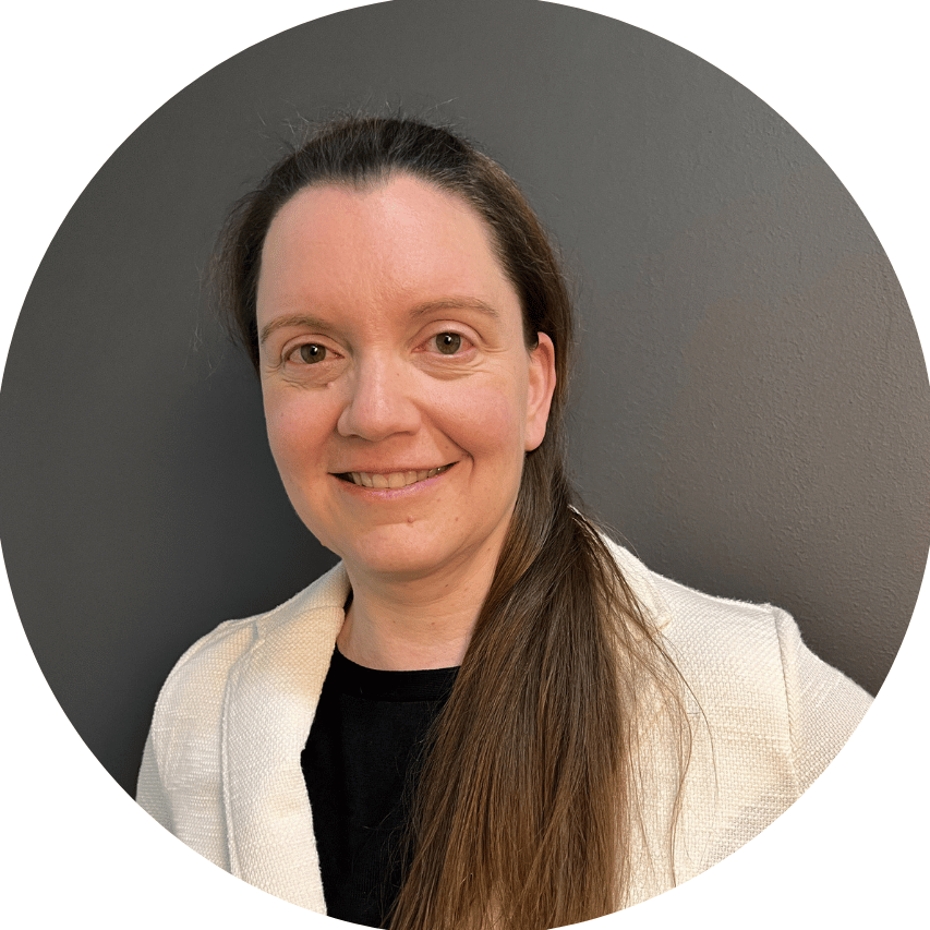 Frau mit langen Haaren in einem runden Rahmen, trägt eine helle Jacke und lächelt.